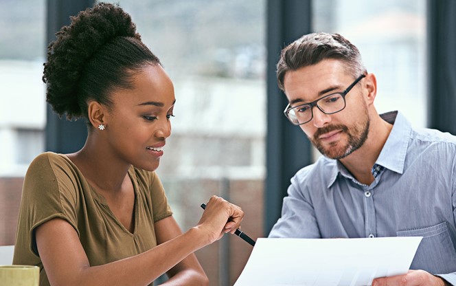 Two Colleagues Having A Meeting In An Office Reviewing A Document