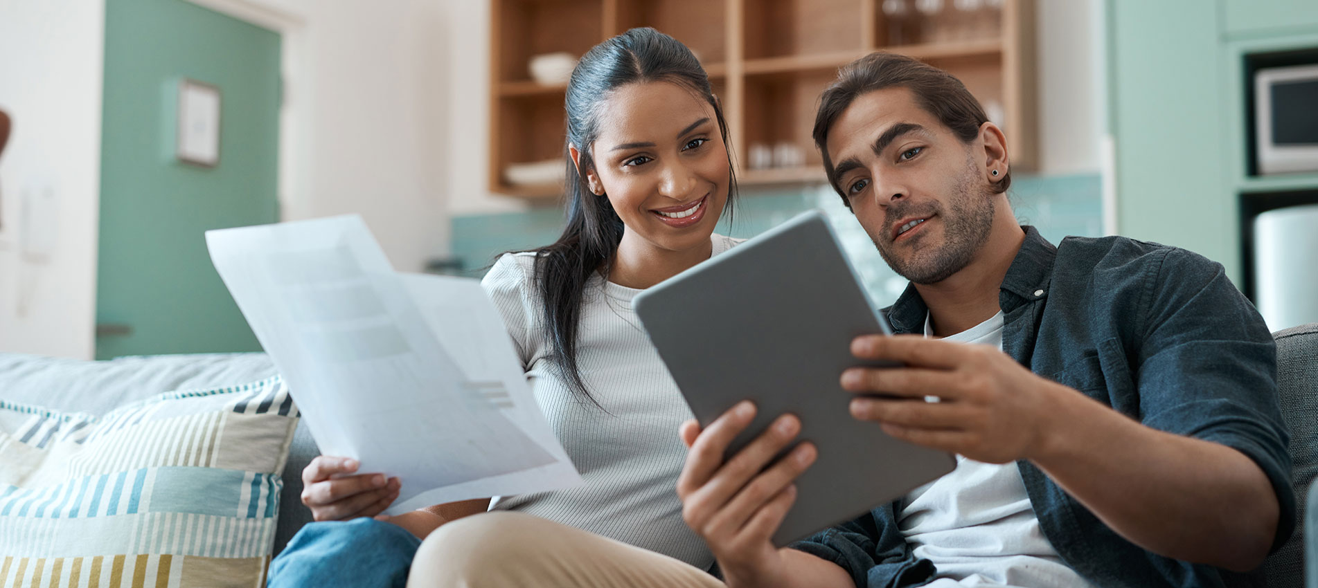 Young Couple Doing Paperwork While Using A Digital Tablet At Home