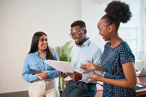 Three Coworkers Stand And Discuss Workplace Issues