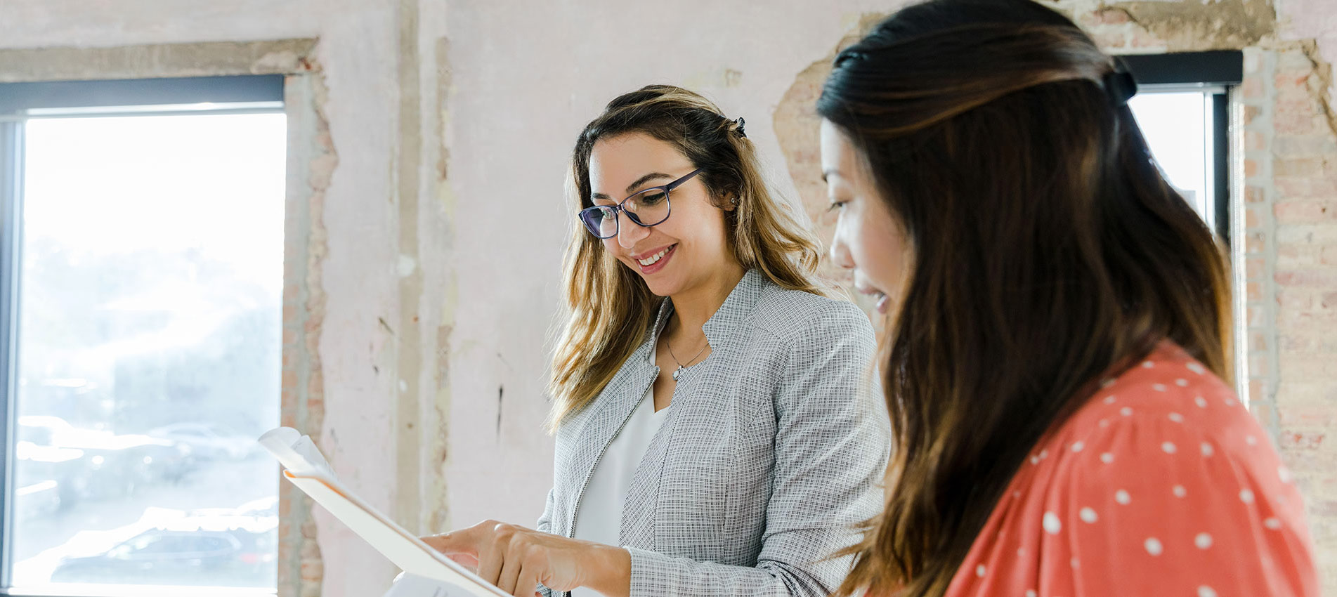 Diverse Businesswomen Smile And Discuss Paperwork