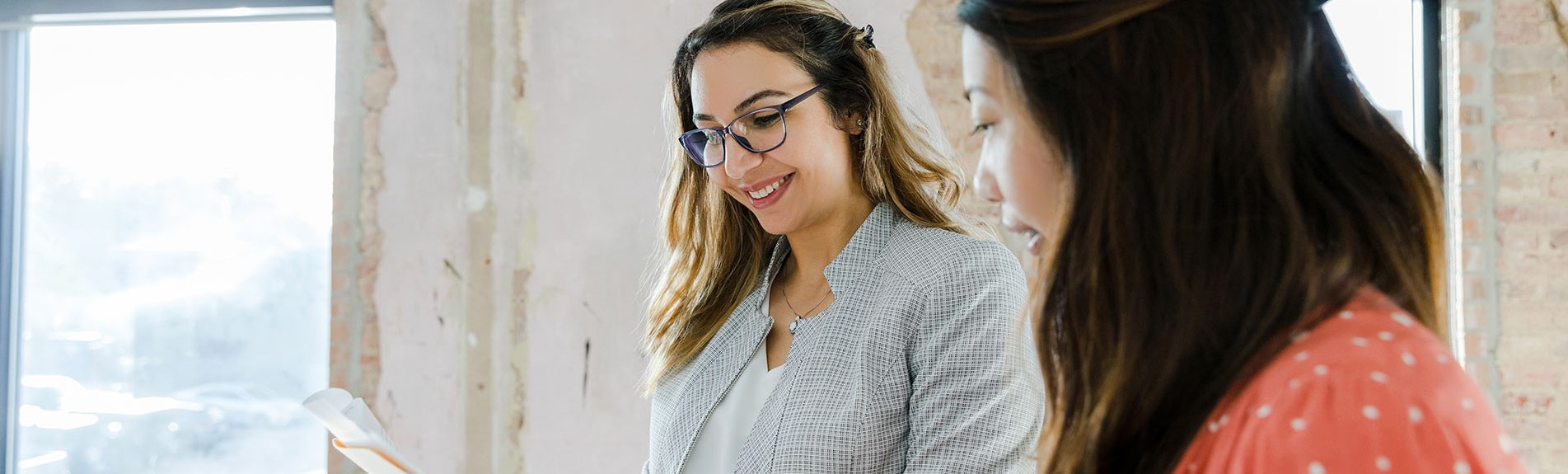 Diverse Businesswomen Smile And Discuss Paperwork