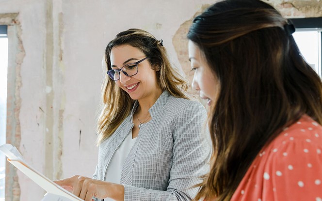 Diverse Businesswomen Smile And Discuss Paperwork