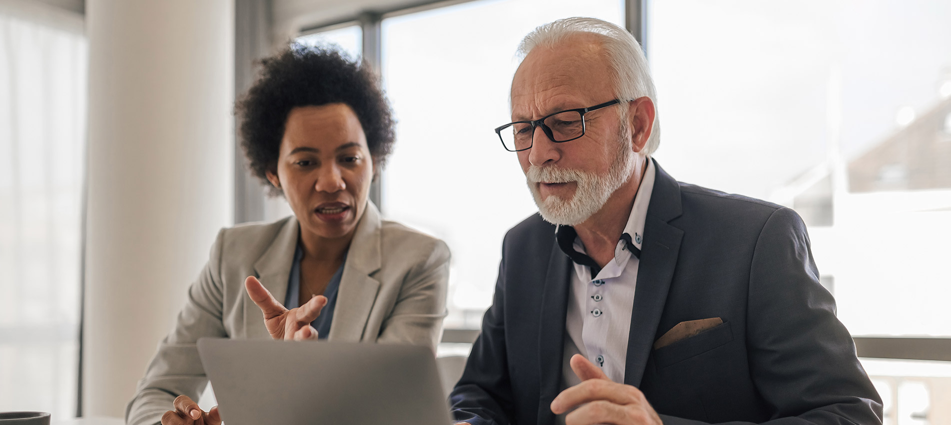 Executive Discussion With Senior Professional While Working On Laptop At Office