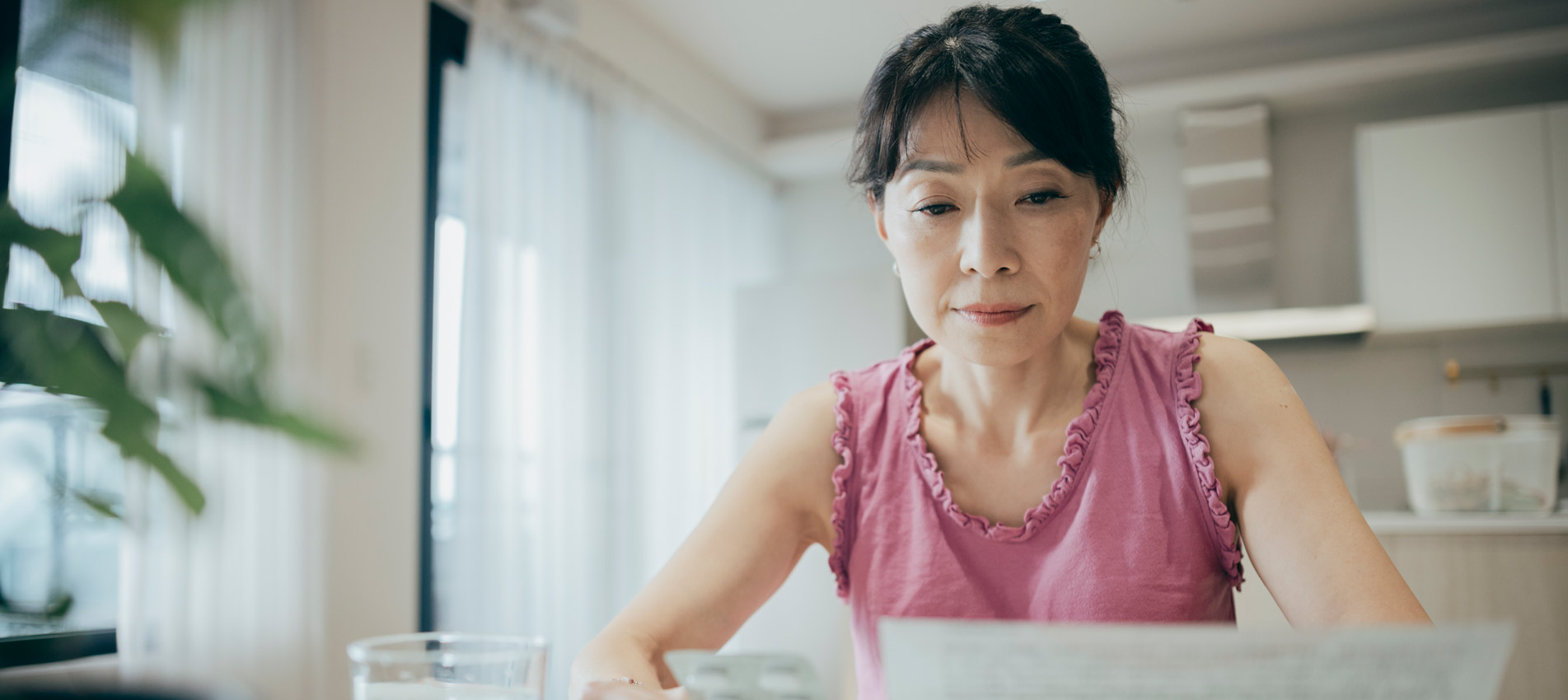 Asian Woman Is Carefully Reviewing The Patient Information Leaflet For Her Medication