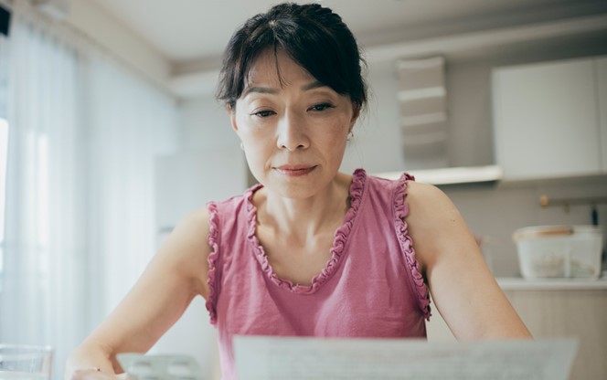 Asian Woman Is Carefully Reviewing The Patient Information Leaflet For Her Medication