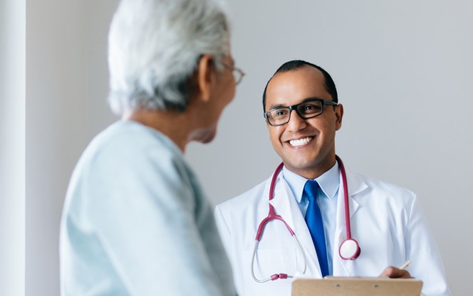 Male Doctor Checking Senior Female Patient And Smiling