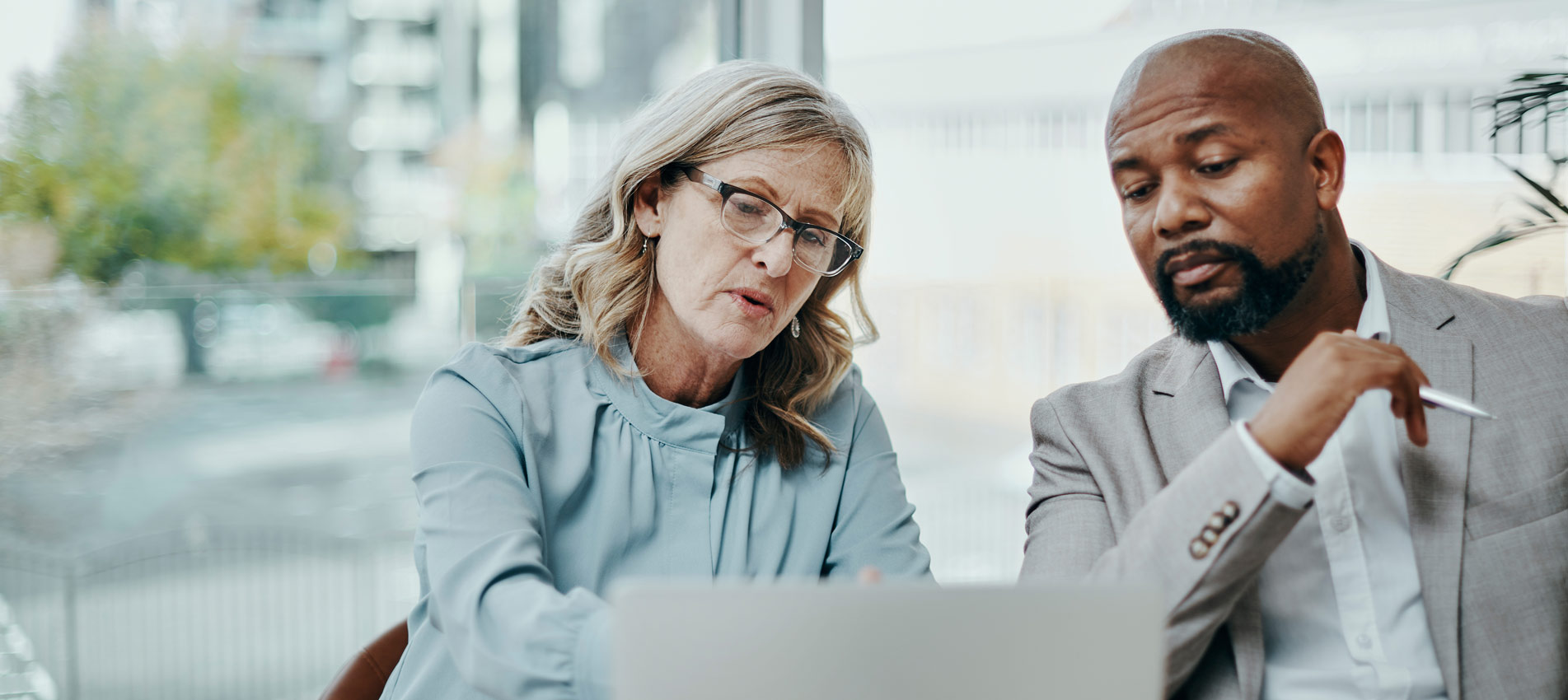 Businessman And Businesswoman Using A Laptop Together In A Modern Office