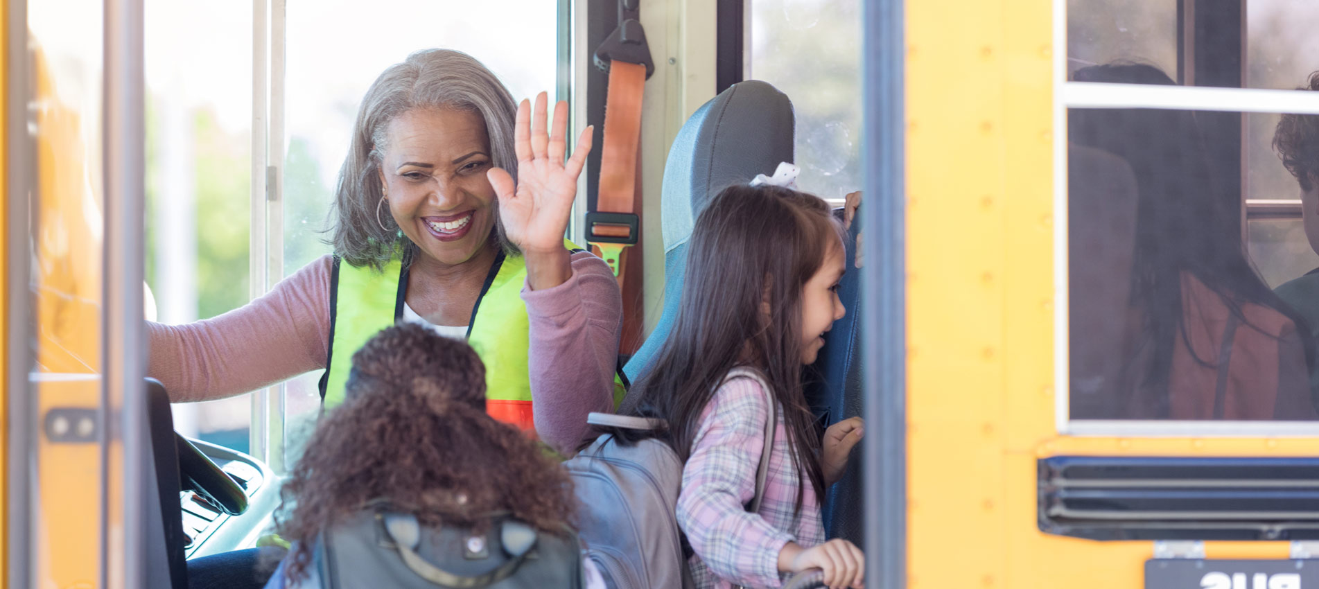 Female Bus Driver High Fives Children Boarding Bus