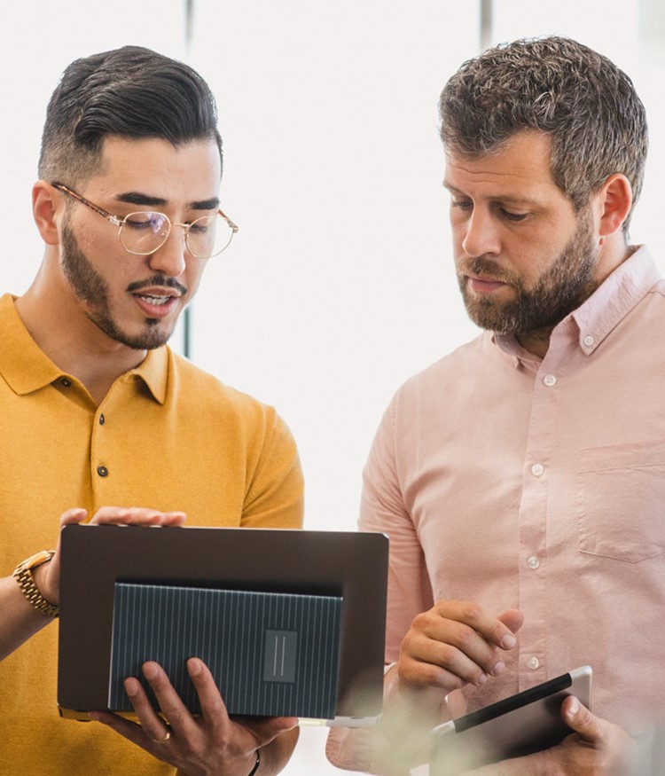 Male Colleagues Using Laptop At Business Meeting With Colleague