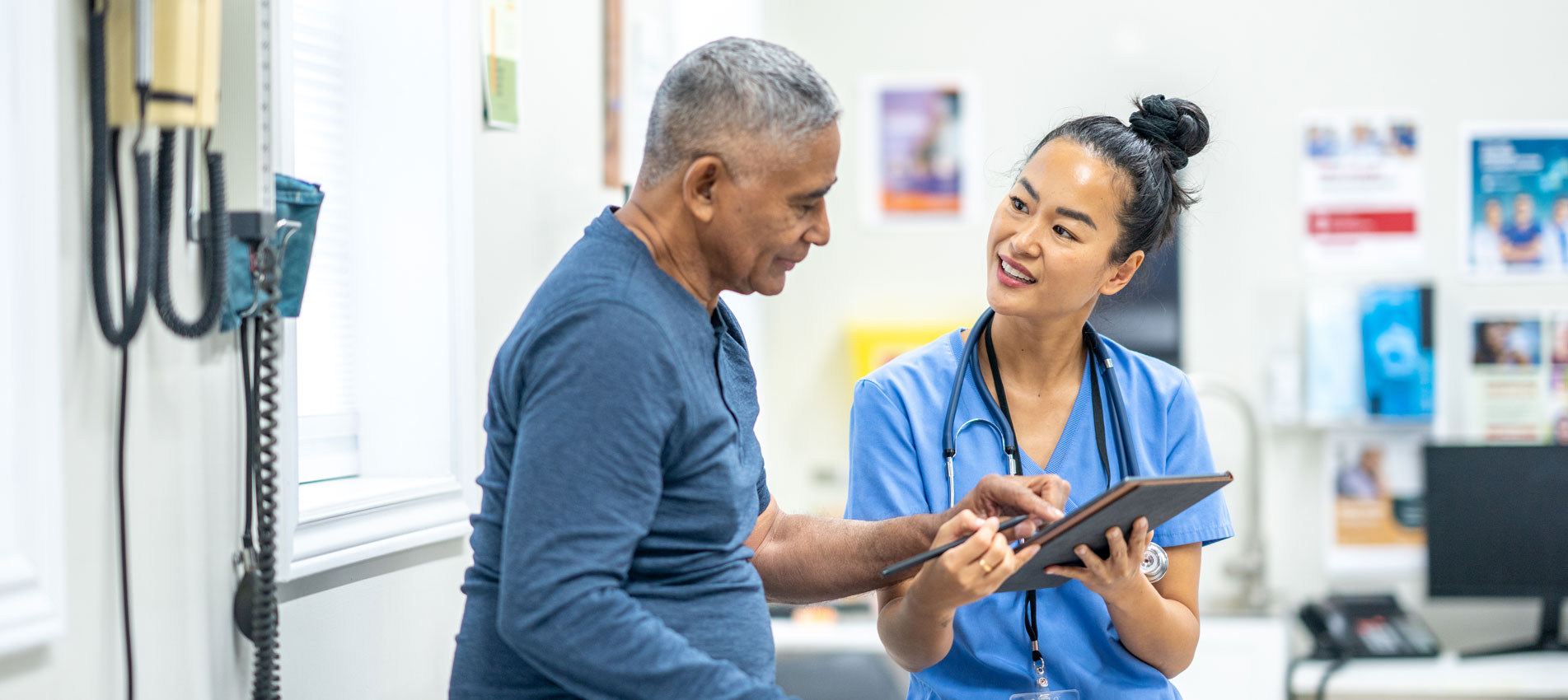 Hispanic Senior Man Having A Routince Checkup With An Asian Nurse