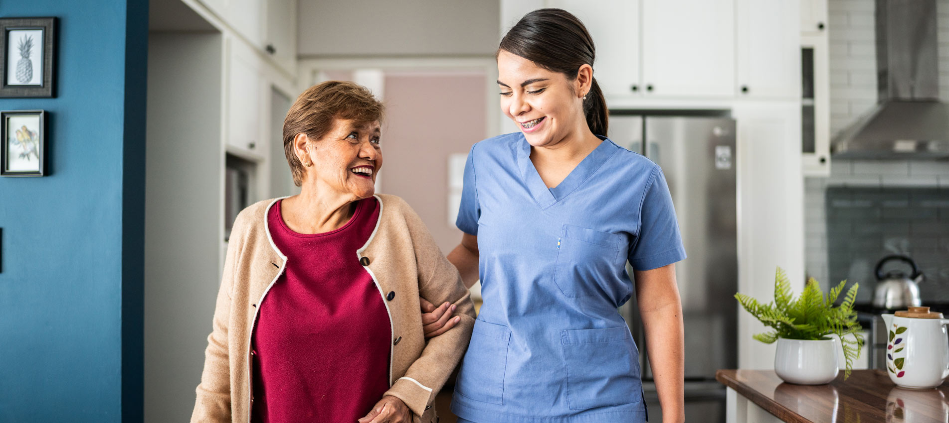 Home Caregiver Helping Senior Woman To Walk At House