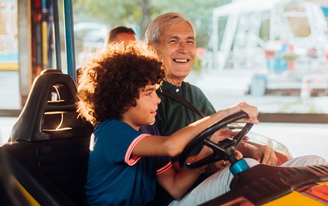 Grandpa And Grandson In A Bumper Car At The Amusement Park