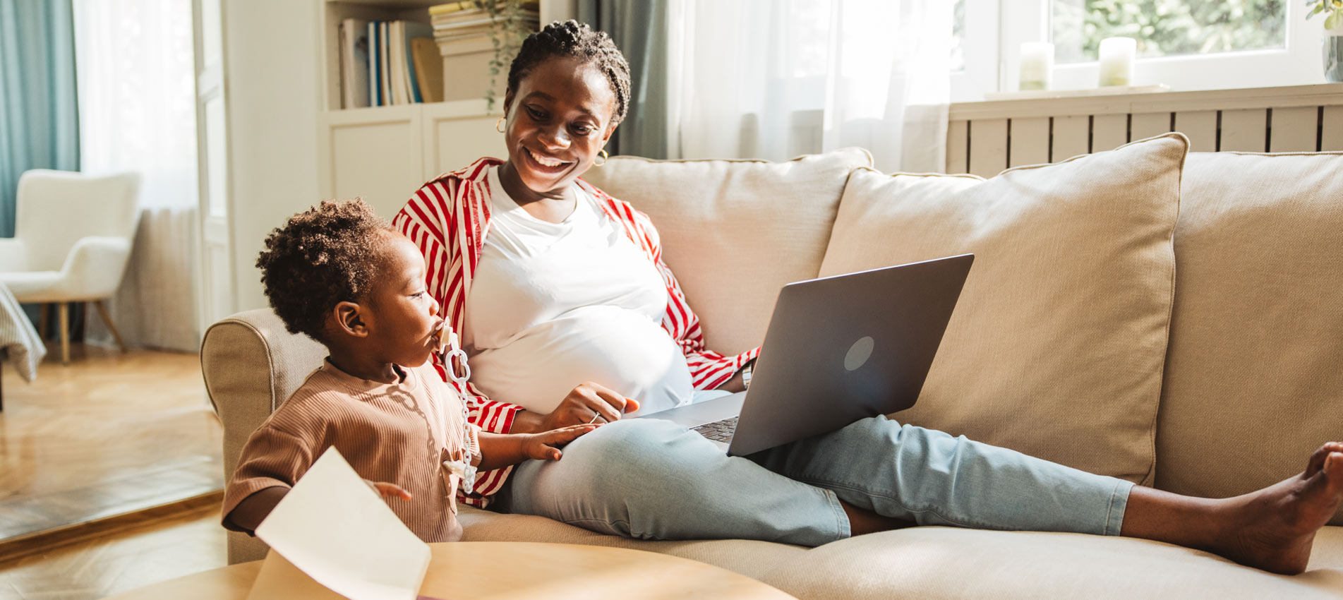 Pregnant Young Woman Working On Laptop With Her Little Son