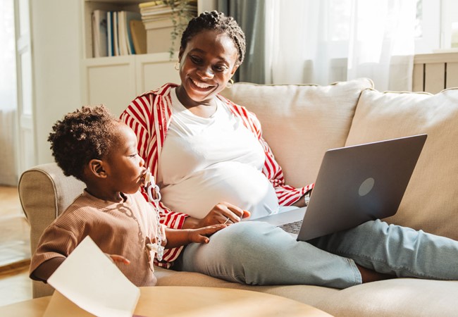 Pregnant Young Woman Working On Laptop With Her Little Son