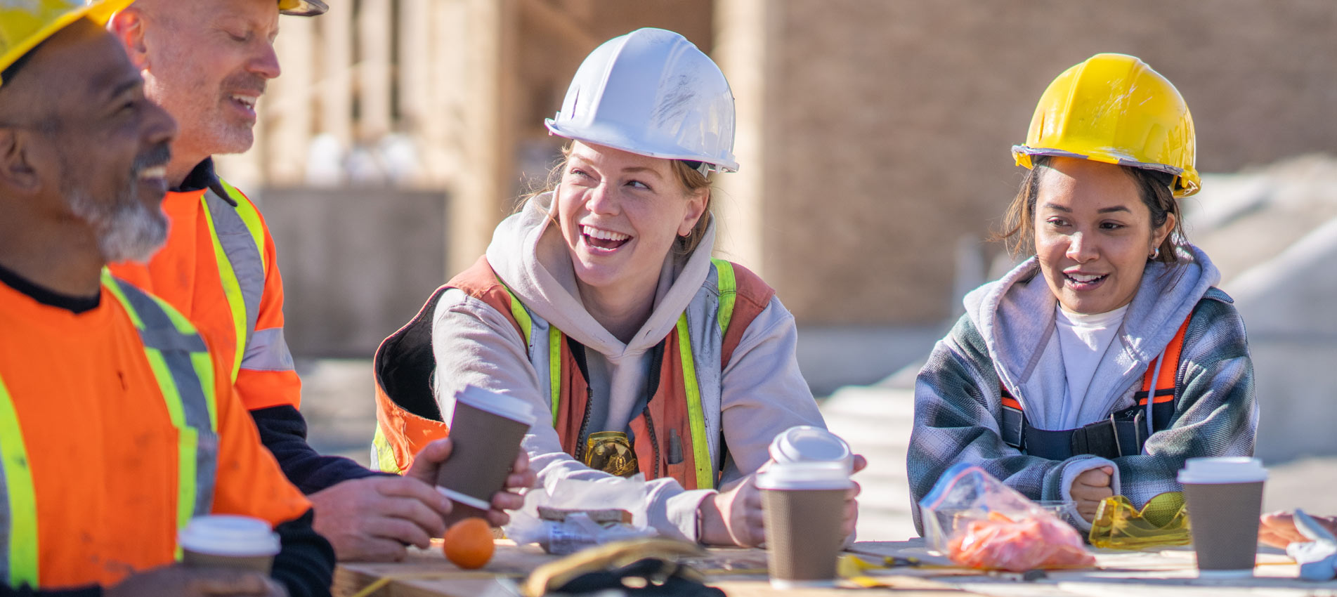 Two Female Construction Workers On A Lunch Break With Colleagues
