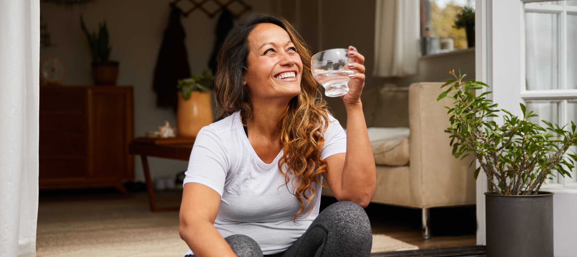 Smiling Mature Woman Sitting On Her Patio Drinking Water