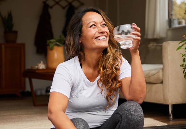 Smiling Mature Woman Sitting On Her Patio Drinking Water