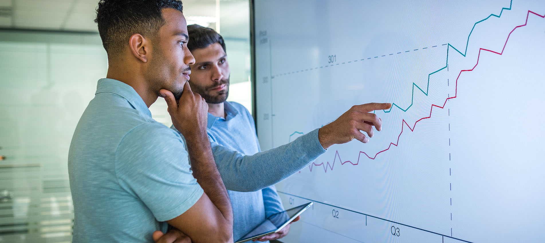 Two Male Colleagues Looking At Data On Screen