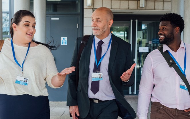 Three Teachers Talking To Each Other While Walking Away From The Building