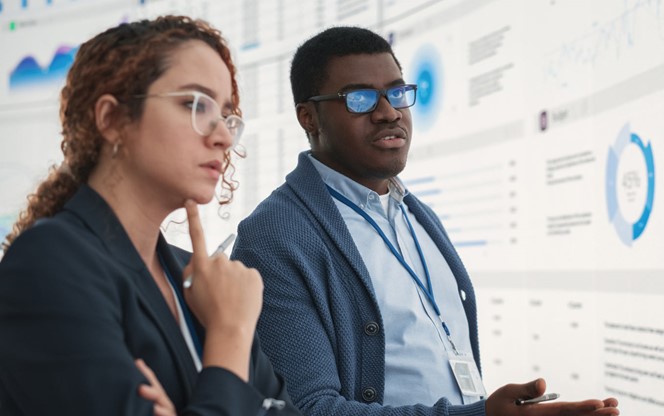 Two Colleagues Analyzing Data On Screen