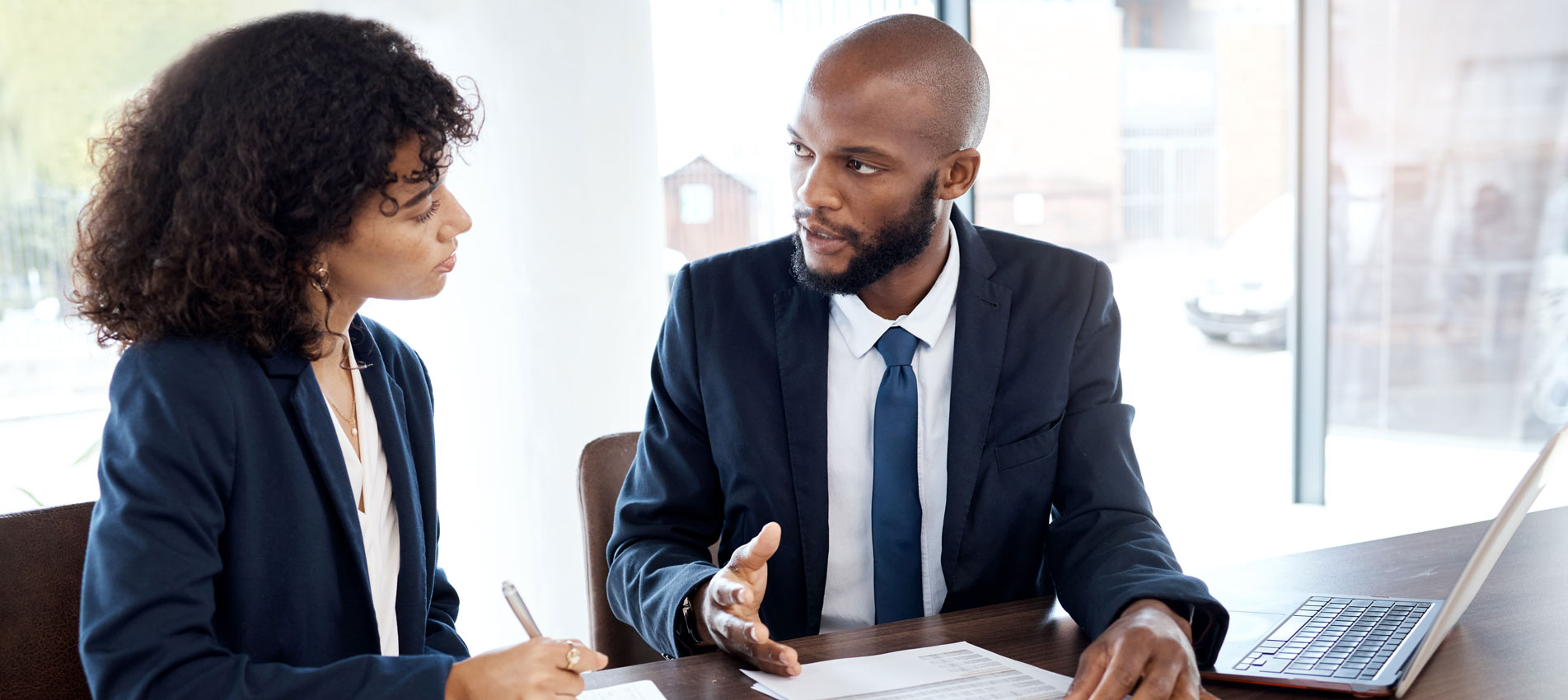 Two Business Partners Discussing Insurance Paperwork At The Office