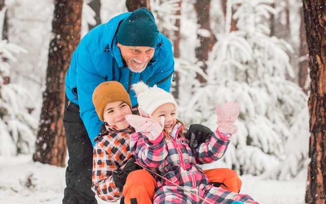 Children With Grandfather Having Fun On A Winter Day