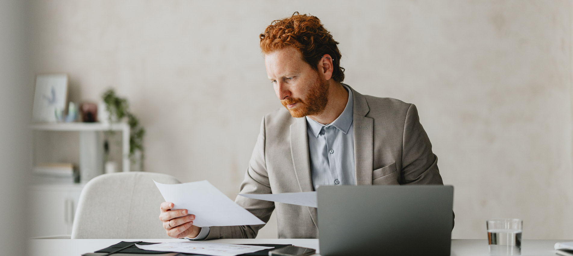 Businessman Reviewing Documents At Modern Office Desk