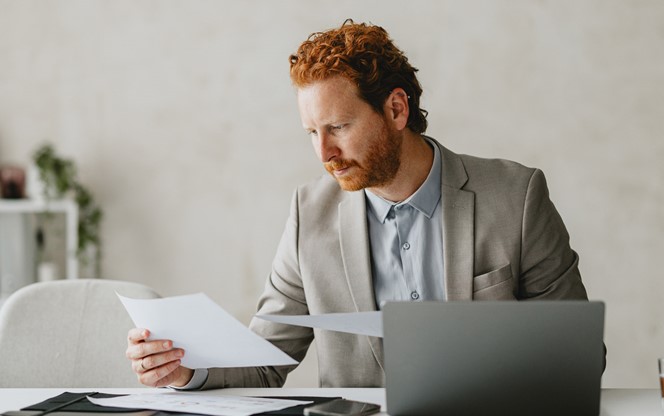 Businessman Reviewing Documents At Modern Office Desk