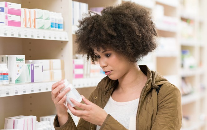 Young Woman Choosing Supplement In Drugstore