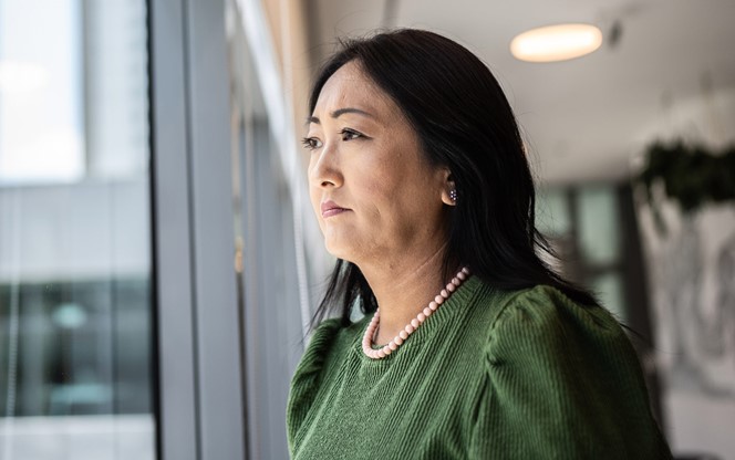 Asian Businesswoman Contemplating Looking Outside Office Window