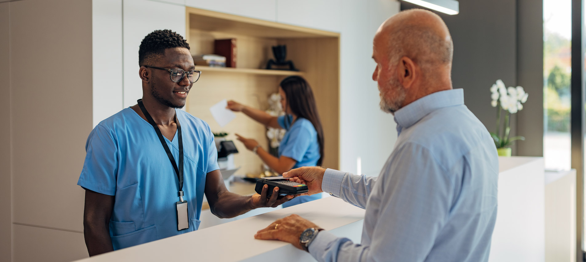 Patient Making Payment With A Credit Card Reader Machine In Modern Clinic