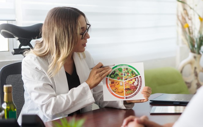 Female Nutritionist Holding Image Of Healthy Eating Plate