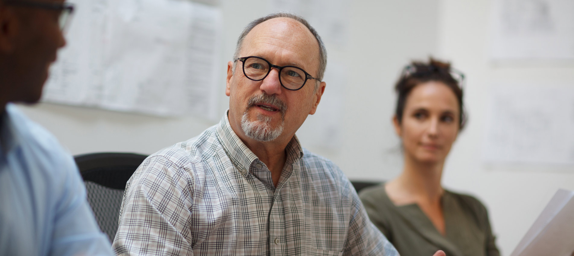 Senior Man Talks Serious Explaining In Meeting With Work Colleagues