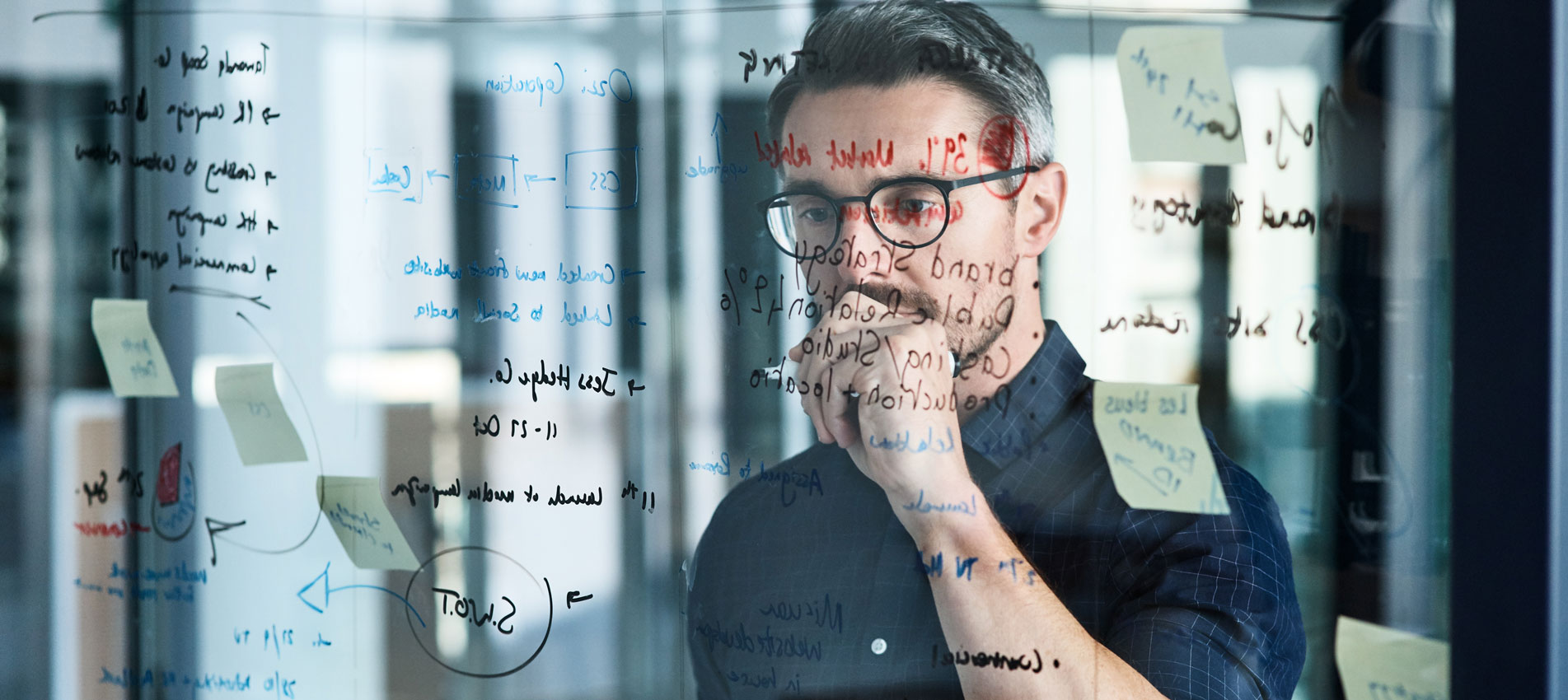 Mature Businessman Brainstorming Notes On A Glass Wall In An Office