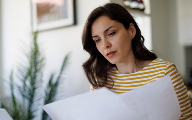 Young Woman Reading A Document At Home