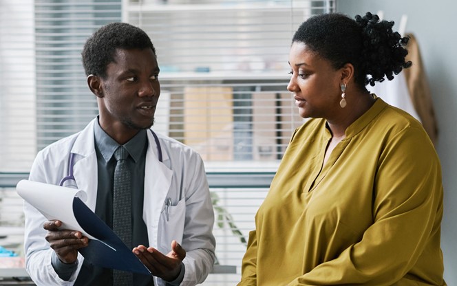Overweight Black Woman Talking To Doctor In Medical Clinic