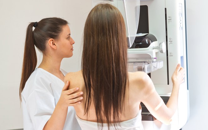 Female Doctor Talking To Patient During Mammography Test In Examination Room