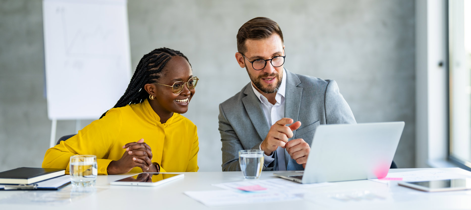 Two Business People Discussing Technology Looking At A Laptop In Office