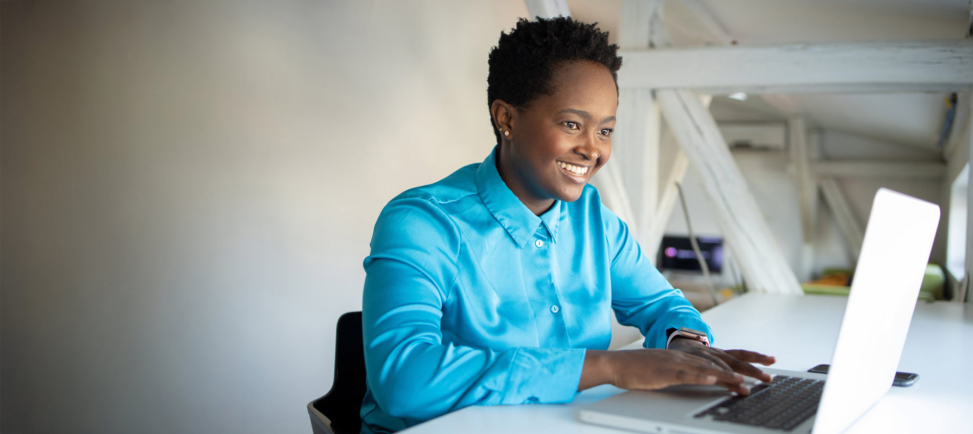 Young Woman Smiling And Working On A Laptop
