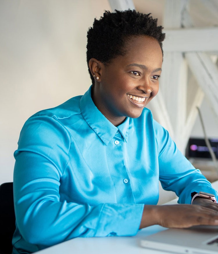 Young Woman Smiling And Working On A Laptop