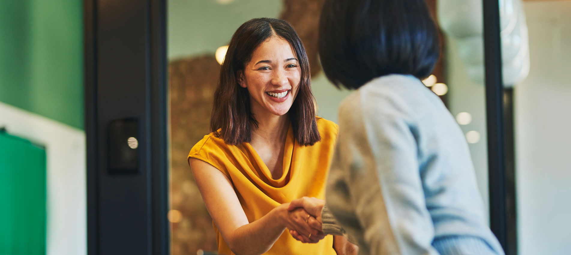 Cheerful Businesswomen Shaking Hands In Meeting Room