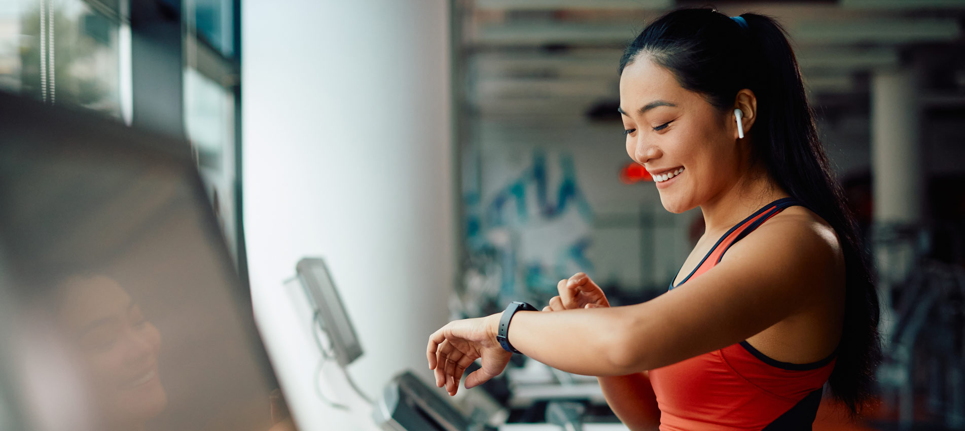 Asia Athletic Woman Using Fitness Tracker While Running On Treadmill In A Gym