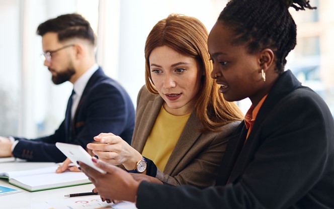 Businesswomen Using Tablet And Reviewing Data Charts