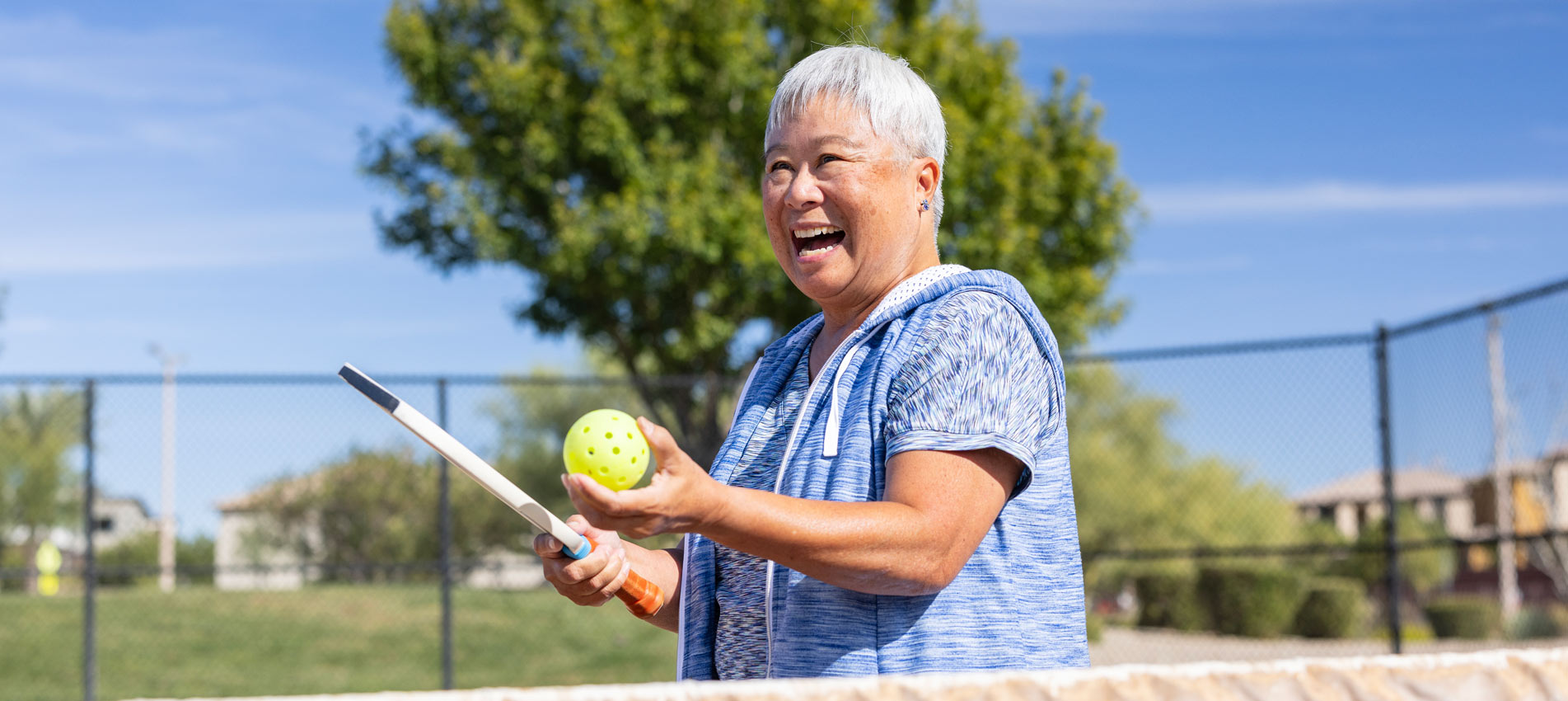 A Senior Asian Woman Having Fun Playing Pickleball At The Park