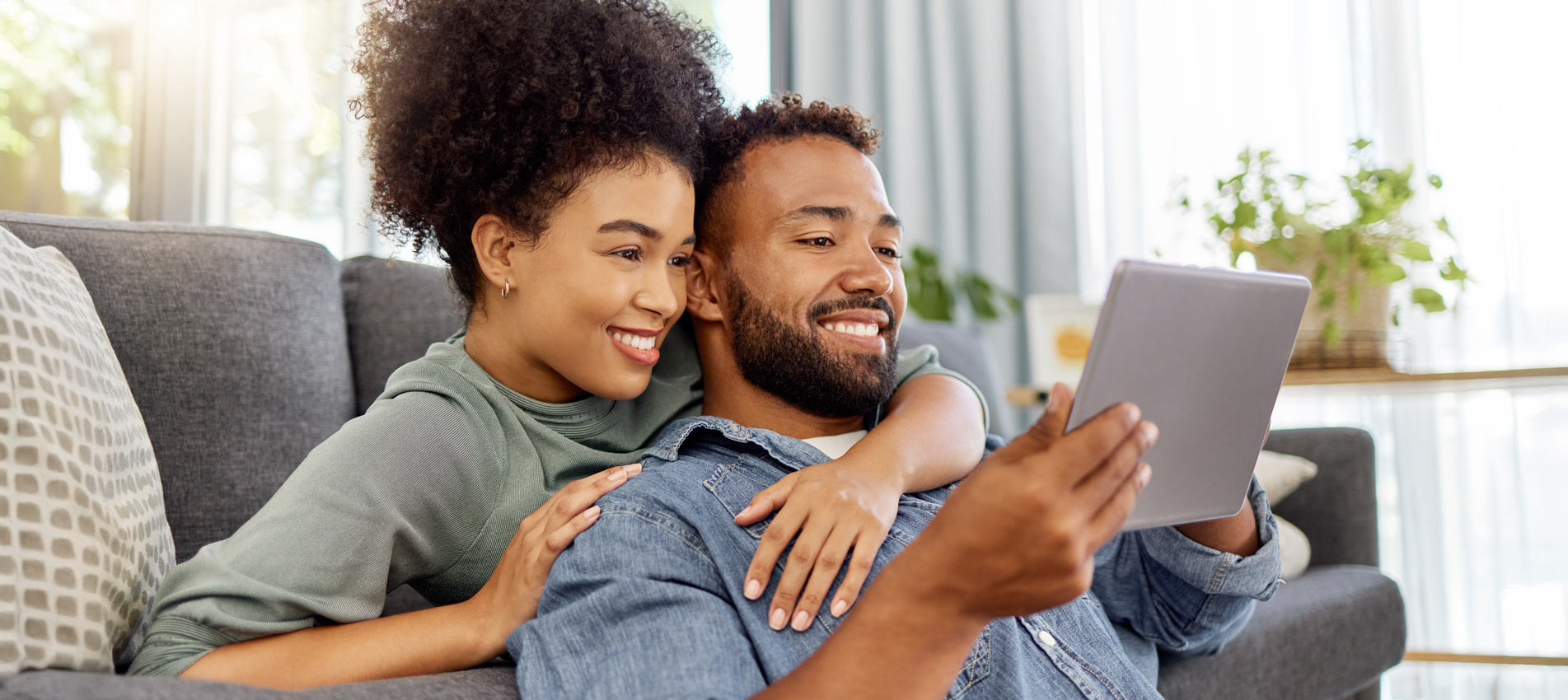 Mixed Race Couple Smiling Using A Digital Tablet