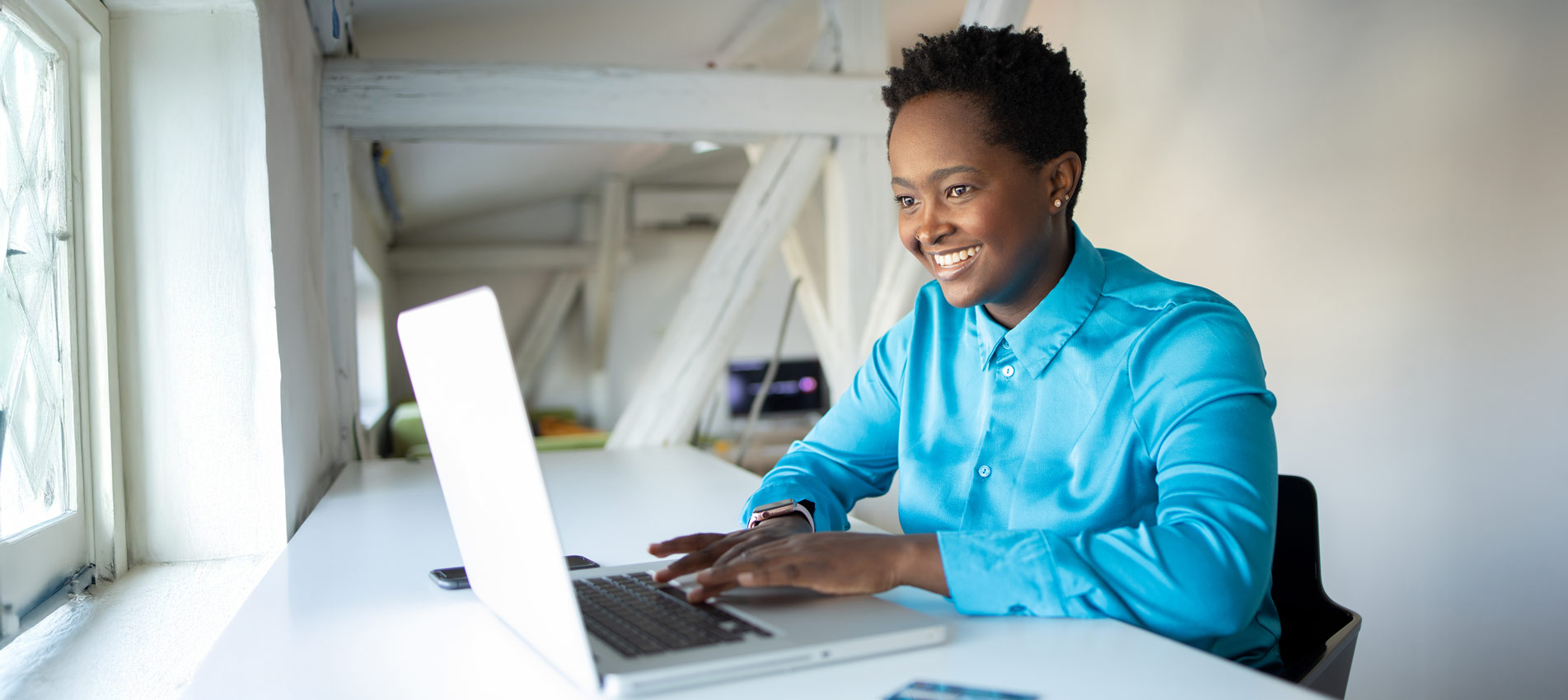 Young Black Woman Smiling And Working On A Laptop