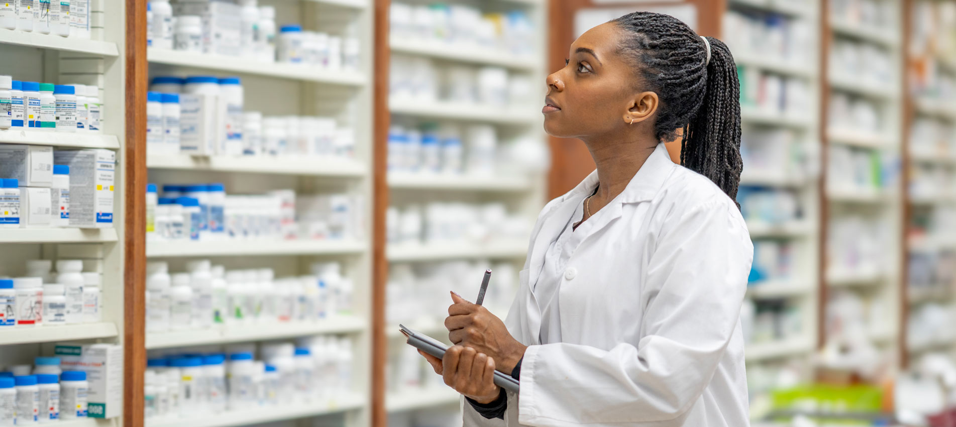 Black Female Pharmacist Observes Medicines On Shelves In A Pharmacy