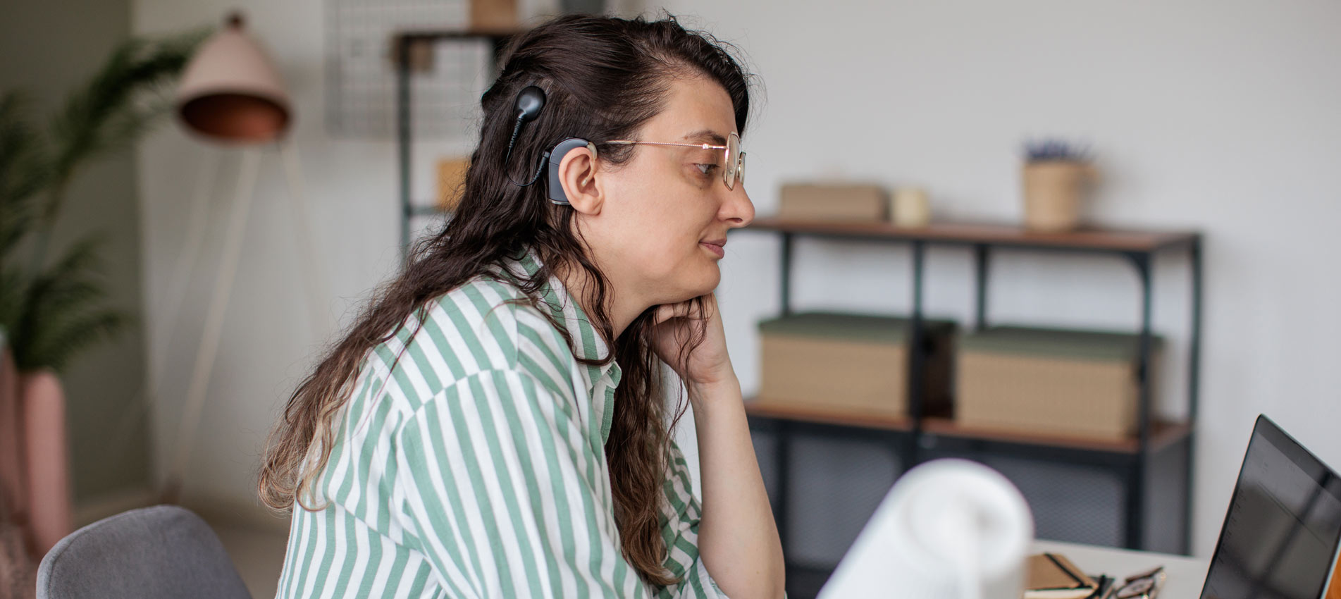 Woman With A Hearing Aid Works On Her Laptop In A Home Office