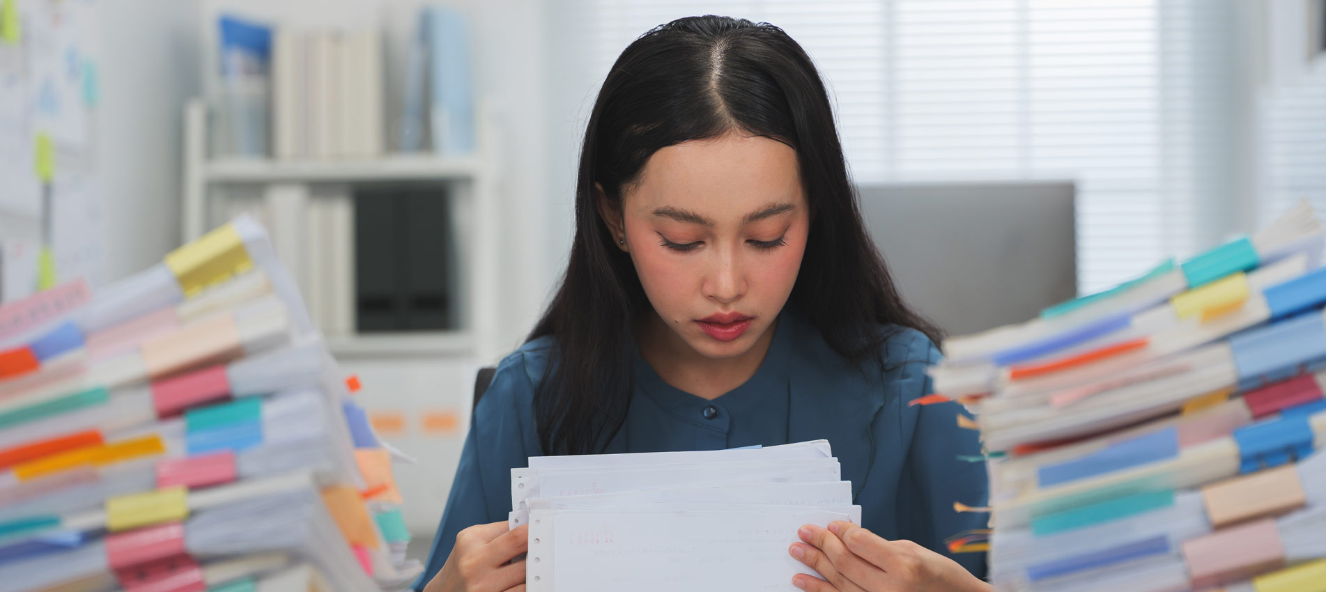 Young Asian Woman Flipping Through Stacks Of Documents At The Office
