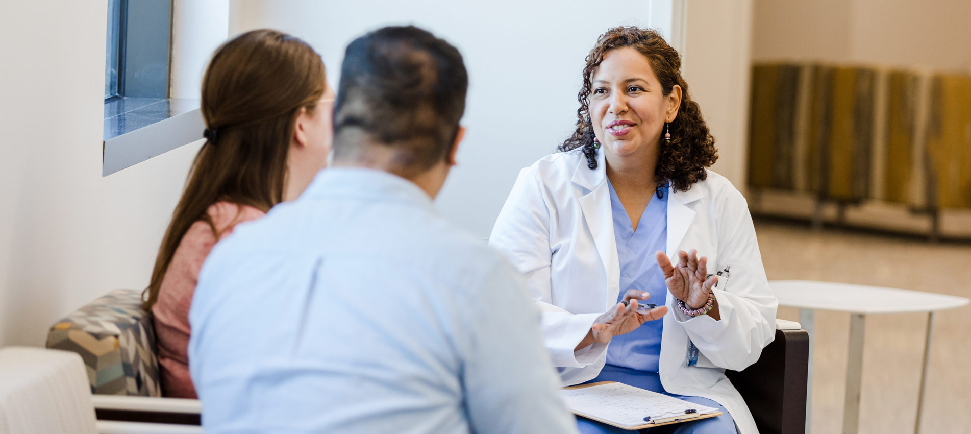 Doctor Counseling Patient Couple In Medical Clinic